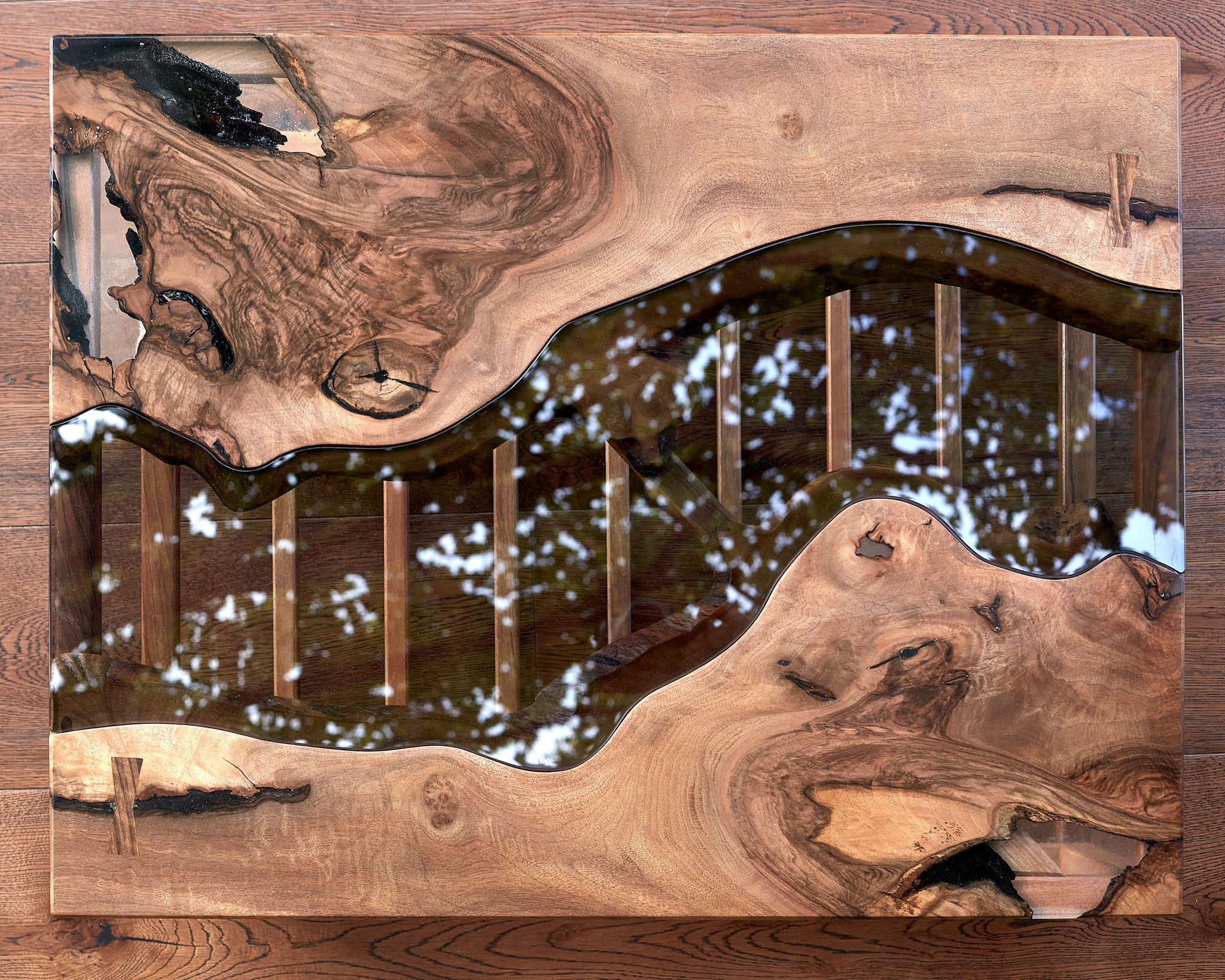 Unveil The Narva River Table, a spectacular Live Edge river table meticulously fashioned from Black Walnut wood by the skilled artisans at Live Edge Tables. This wood is celebrated for its unparalleled strength and durability, guaranteeing that this table boasts the utmost quality. Its contemporary design, highlighted by a natural raw edge, effortlessly harmonizes with any home decor. The wood's breathtaking beauty and the flawless craftsmanship combine to create an indelible and lasting impression.