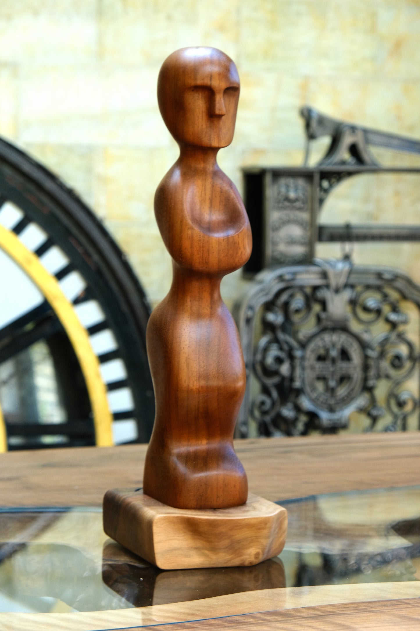 Explore the Artistry of 'Iroko Prayer' with Our Live Edge Sculpture. This enchanting wooden statue is a masterpiece, painstakingly handcrafted to grace your home with elegance. Made from the exquisite Iroko wood, renowned for its healing properties, this exceptional sculpture showcases a beautifully hand-carved wooden figurine, delicately mounted on a sleek black walnut raw edge plinth. It's a genuinely distinctive wood sculpture that imbues any space with enduring beauty.